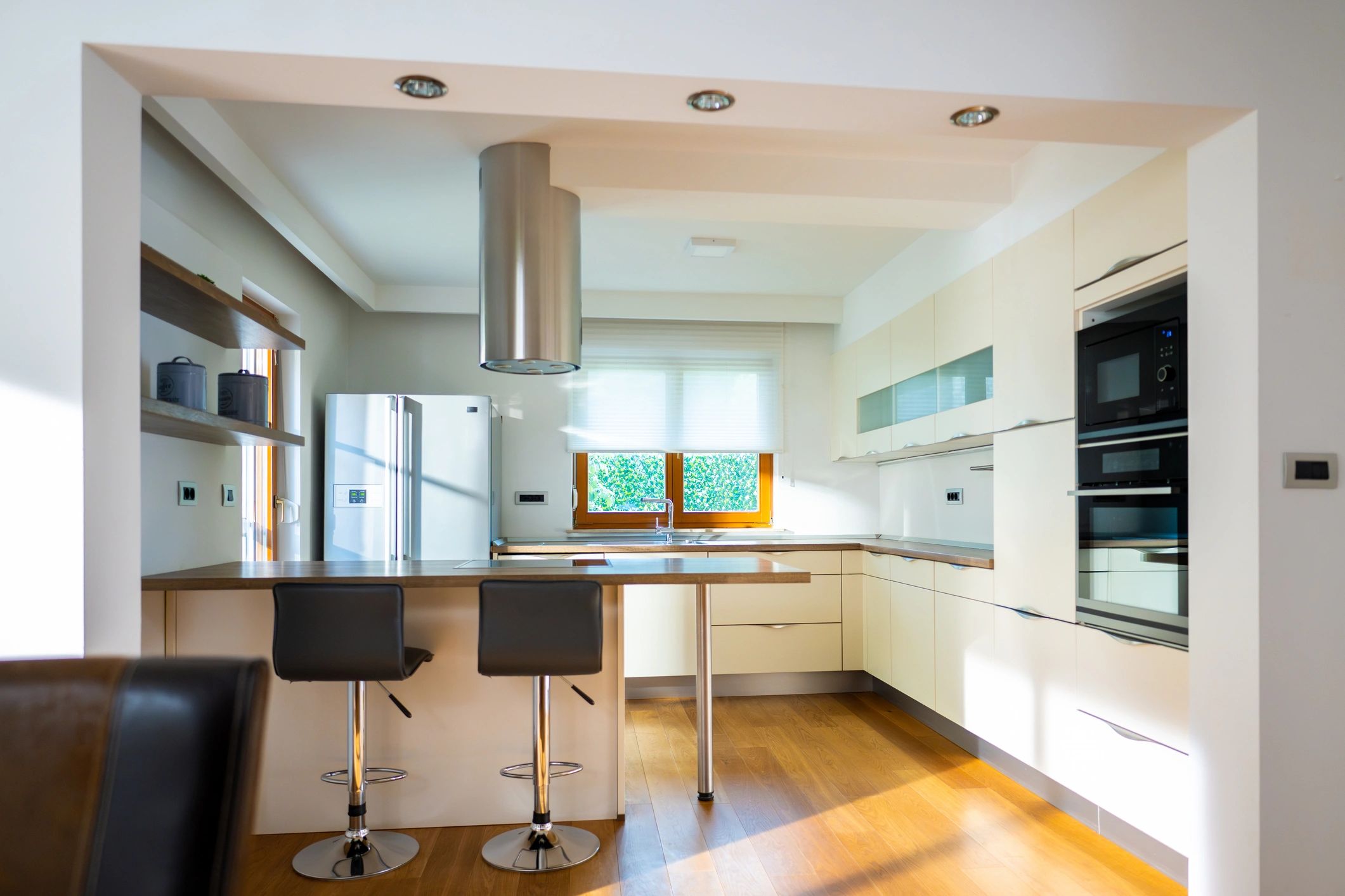 Sunlit modern kitchen with white cabinetry and wood floors